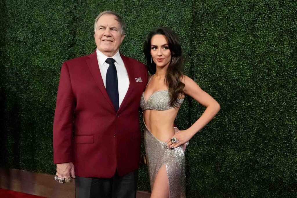 Jordon Hudson enjoys a basketball game while Bill Belichick sleeps beside her